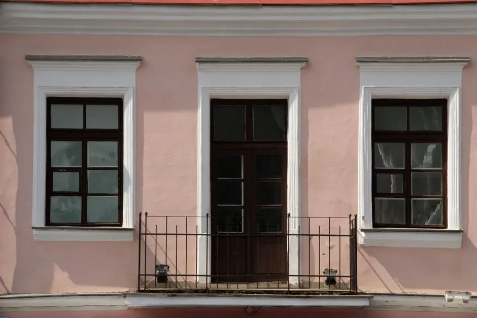 Charming pink building facade featuring symmetrical windows and a small balcony.